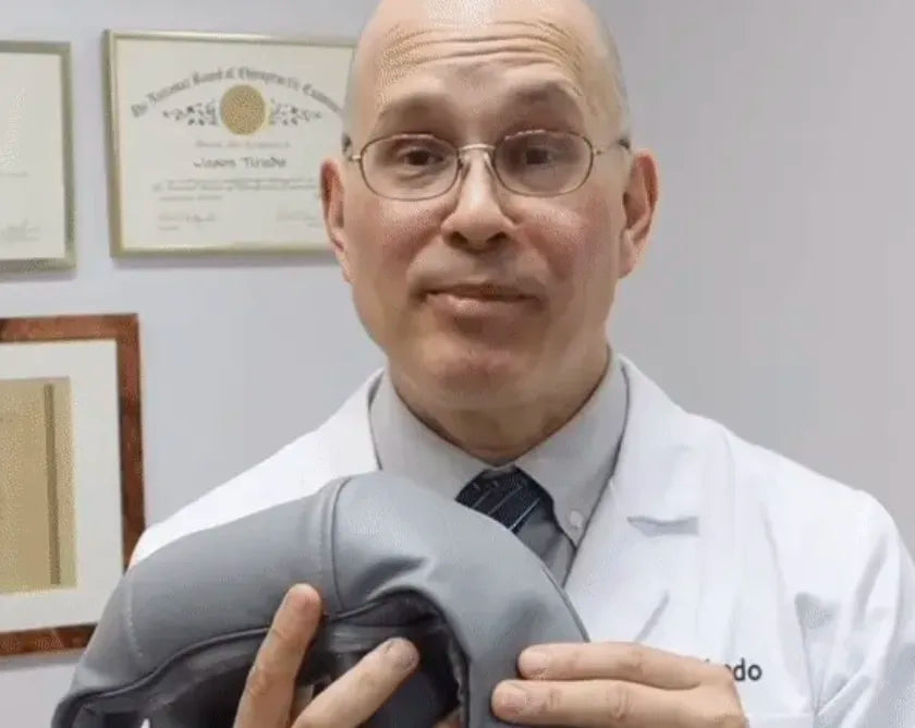 Chiropractor in white lab code holding TheraPexa neck and shoulder massager in clinic, recommending cordless deep tissue massage for trap pain relief