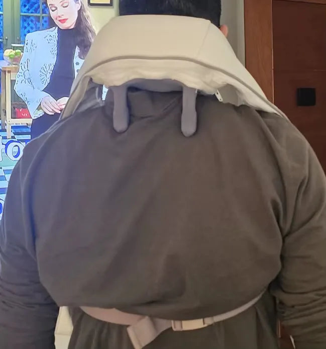 Man wearing the TheraPexa neck and shoulder massager while watching TV, showing hands-free back view and adjustable strap fit.
